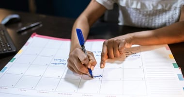 Person writing on paper calendar