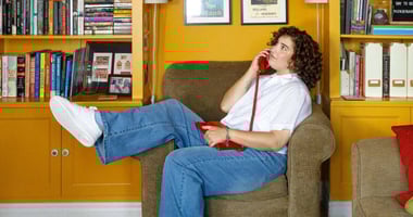 Renee Yoxon poses on a sofa while holding a corded phone to her ear