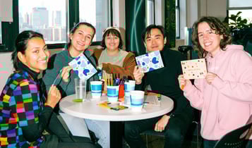 Friends hold up their letters and smile for a photo