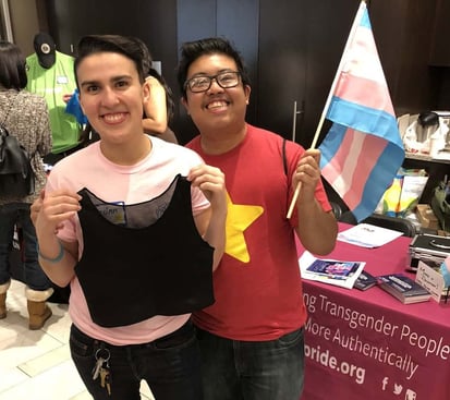 Two trans youth holding their free chest binders
