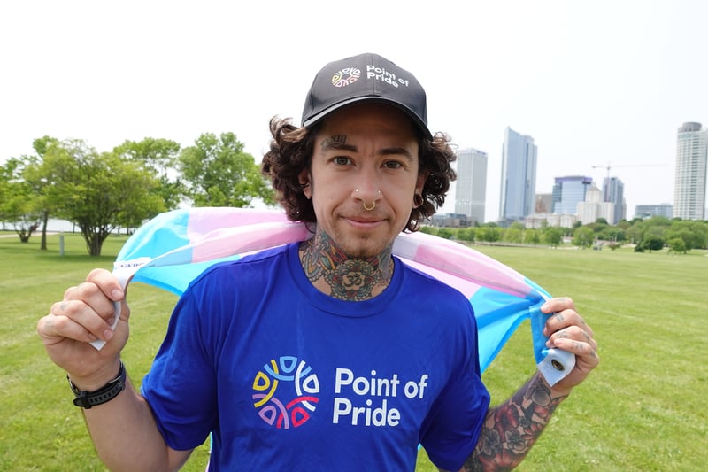 A happy athlete wearing a Point of Pride tee and a trans flag like a cape