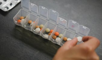Close-up of a hand putting pills into a pill organizer