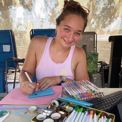 Smiling volunteer looks at camera while writing notes of support