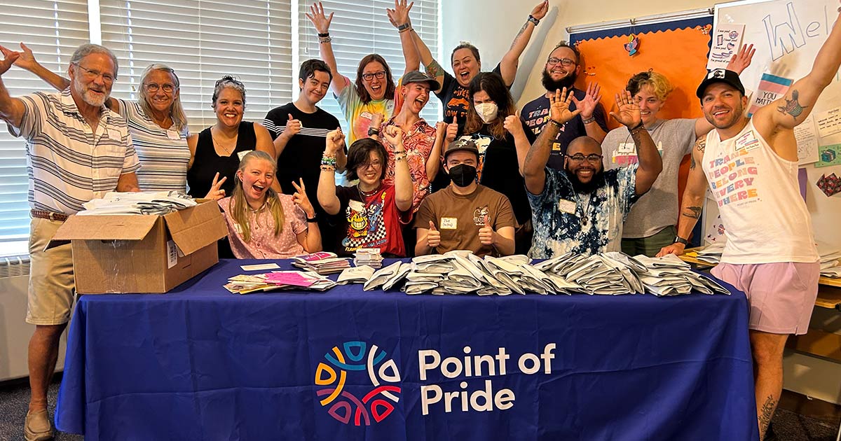 Volunteers and staff cheer behind table with packaged binders