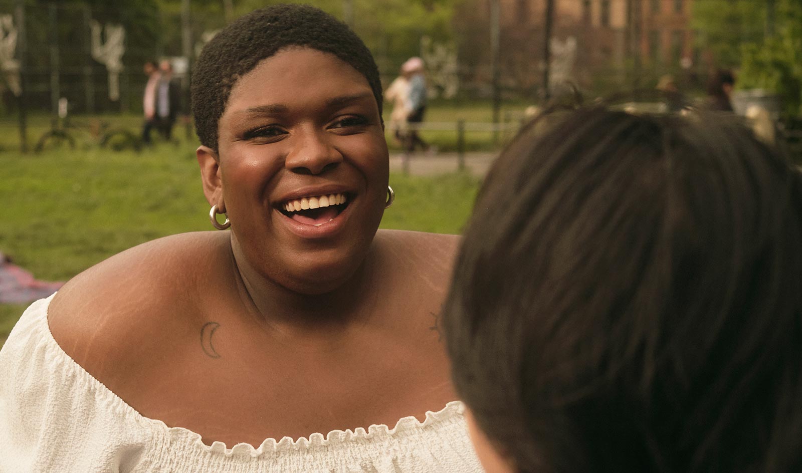 Close-up of a happy trans person talking to their friend at the park