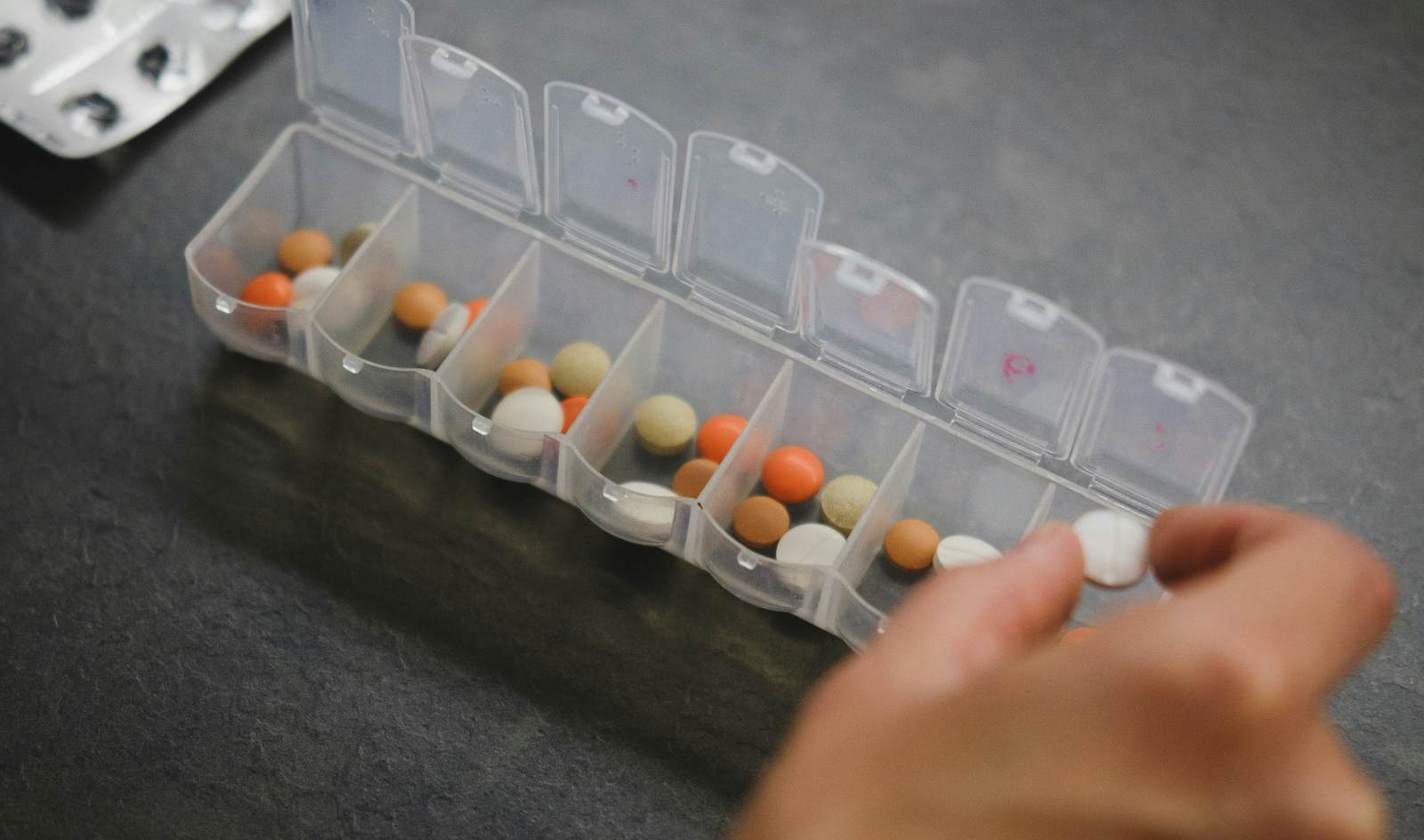 Close-up of a hand putting pills into a pill organizer