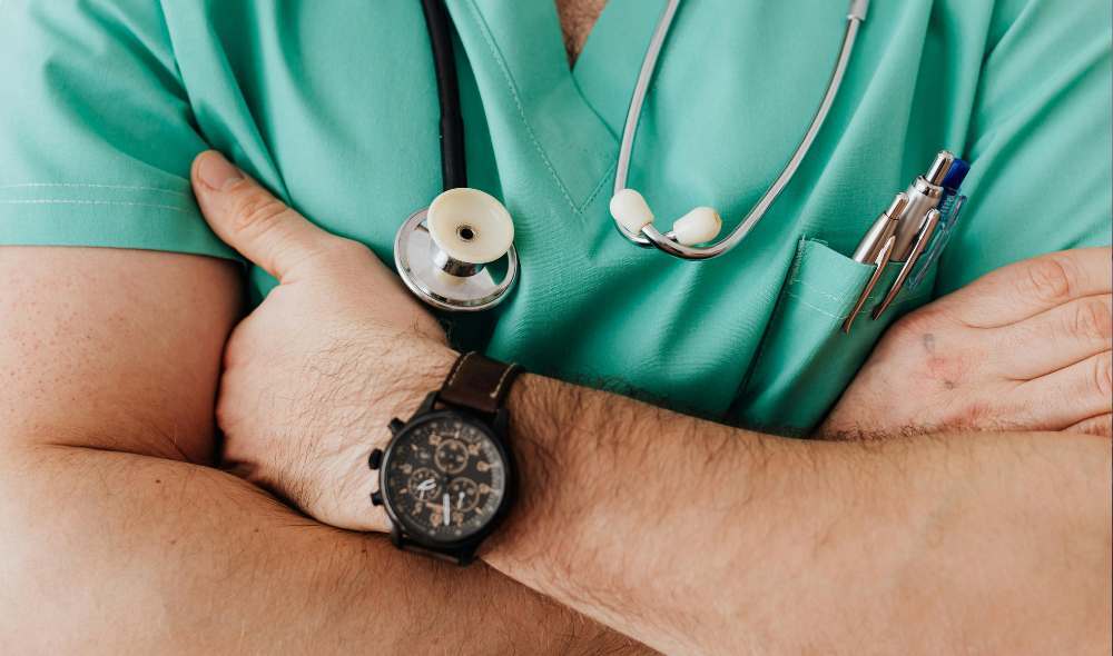 Close-up shot of surgeon crossing arms over green scrubs