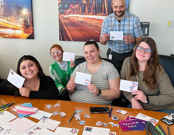 Group of people smiling and holding up handwritten notes of support