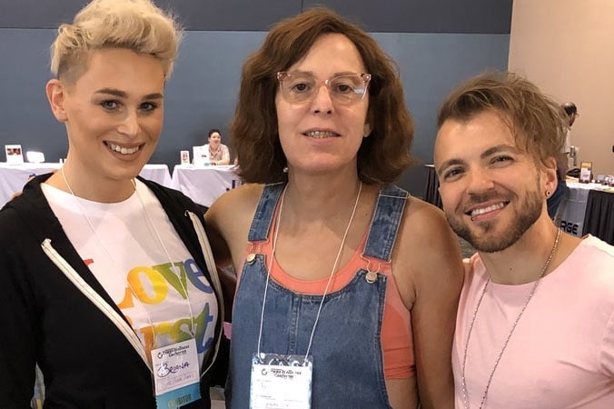 Three smiling trans folks pose for a photo