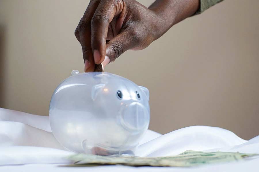 Hand depositing coin into piggy bank