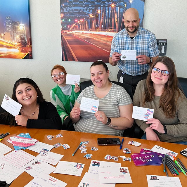 Members of Holman HQ's LGBTQ+ ERG hold up their finished letters